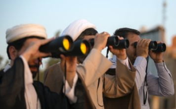three men using binoculars