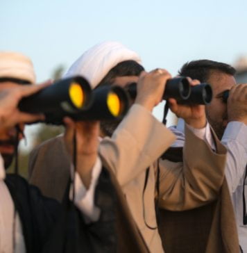three men using binoculars